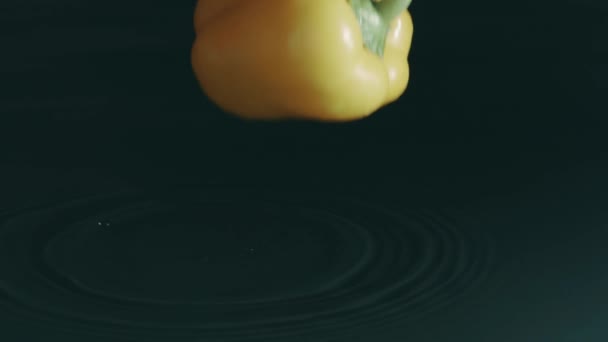 Κίτρινη πιπεριά πέφτει σε ρηχή επιφάνεια του νερού. Αργή κίνηση, πυροβολισμός στο κόκκινο — Αρχείο Βίντεο