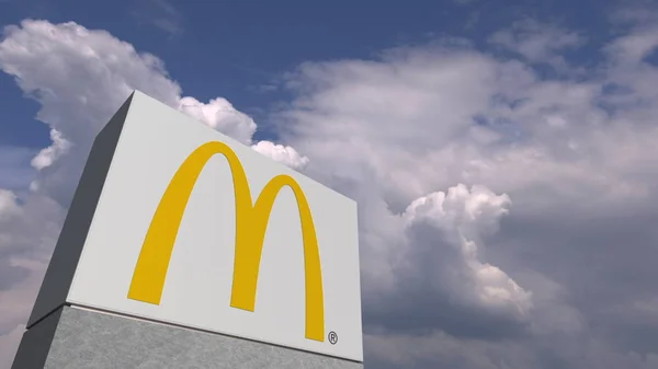 Logo McDonaldů na stojánek proti zatažené obloze, redakční prostorové vykreslování — Stock fotografie