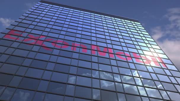 Logo typ Exxon mobil på en Media fasad med reflekterande molnigt himmel, redaktionell animation — Stockvideo