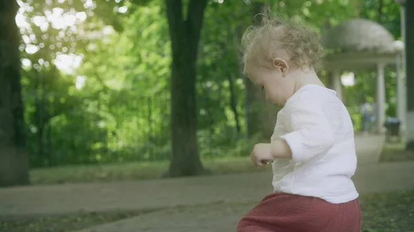 Liten blond bebis flicka promenader i parken på en sommar dag — Stockfoto