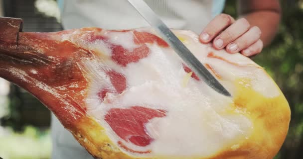 Man afsnijden reuzel van Jamon been, een soort van gedroogde ham uit Spanje. Geschoten op rood — Stockvideo