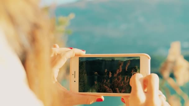 Femme tourne une vidéo de paysage avec son smartphone sur la rive du lac par une journée ensoleillée. Tourné sur caméra rouge — Video