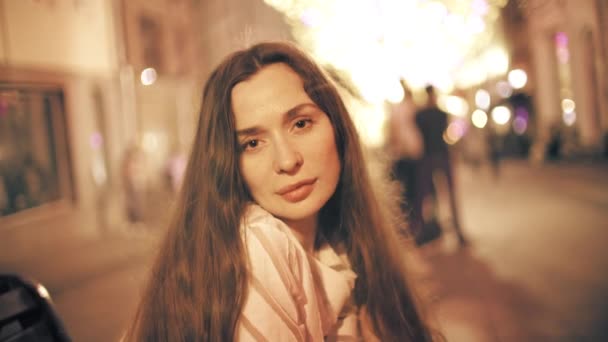 Портрет красивой молодой женщины на фоне освещенной пешеходной зоны — стоковое видео