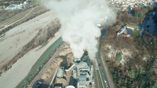 Воздушный кадр дымящихся труб небольшого завода в долине реки, северная Италия — стоковое видео