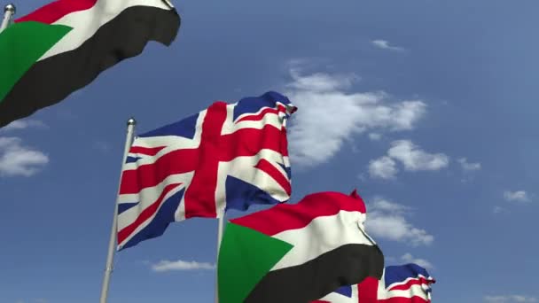 Waving flags of Sudan and the United Kingdom on sky background, loopable 3D animation — Stock Video