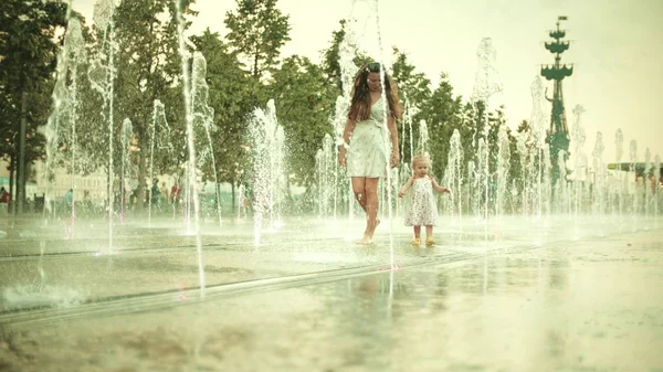 Mamma och hennes lilla dotter ha kul medan du går i fontänen, slow motion shot — Stockfoto
