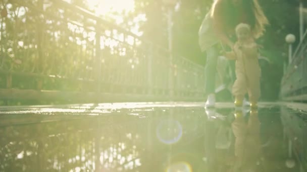 Happy Baby Girl i vattentät regnrock och regn stövlar går på vattenpölar, slow motion shot — Stockvideo