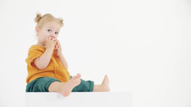 Cute blonde baby girl eats apple against white background — Stock Video
