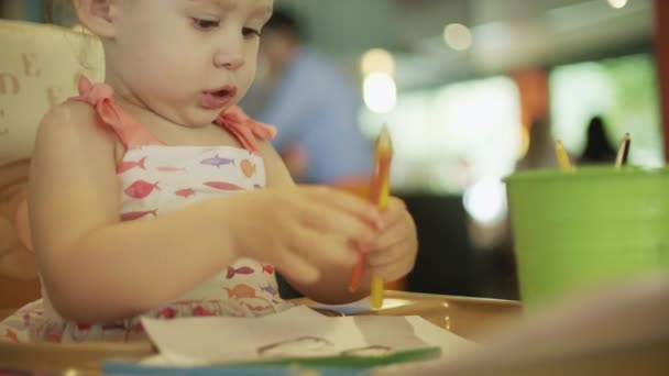Девочка кладет цветные карандаши в ведро на стол — стоковое видео