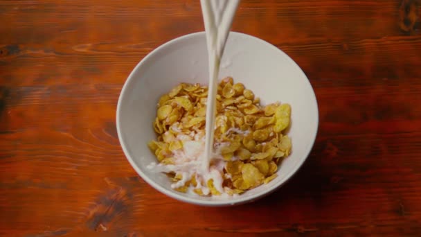 Gieten van melk in de kom met maïsvlokken op rode houten tafel, Super Slow Motion schot — Stockvideo