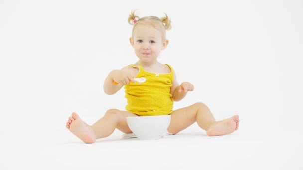 Funny baby girl eats her meal with a spoon — Stock Video