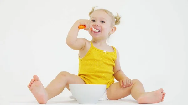 Sorrindo bebê menina comendo seu café da manhã no fundo branco — Fotografia de Stock