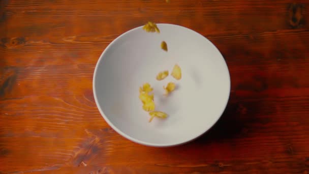 赤い木製のテーブルのプレートにトウモロコシのフレークを注ぐ、スーパースローモーションショット — ストック動画