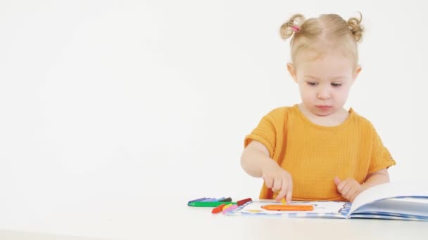 Blonde baby coloring unknown picture with a yellow crayon — Stock Video