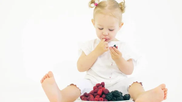 귀여운 아기는 밝은 배경에 열매를 먹는다 — 스톡 사진