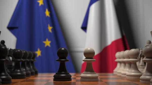 Bandiere dell'UE e della Francia dietro la scacchiera. Il primo pedone si muove all'inizio del gioco. Rivalità politica rendering concettuale 3D — Foto Stock