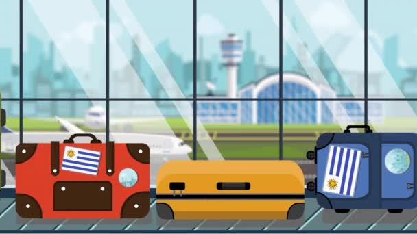 Koffers met Uruguayaanse vlag stickers op Bagage carrousel in luchthaven, close-up. Toerisme in Uruguay gerelateerde loop bare cartoon animatie — Stockvideo