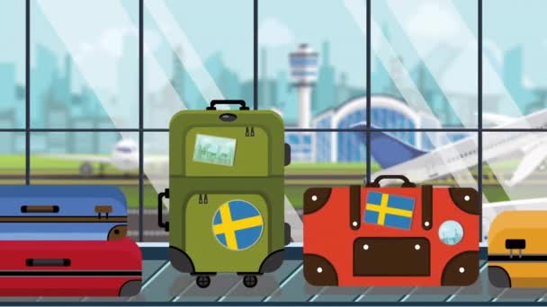 Kufry se švédským praporkem jsou nálepky na kolotoči zavazadel na letišti, zblízka. Švédský turismus s smykliči, Kreslená animace — Stock video