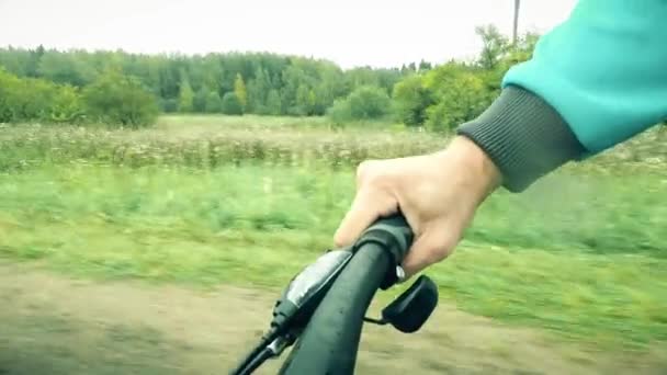POV kerékpáros lövés. Mans kezét a kerékpáros markolat és váltó közben lovaglás erdei úton egy esős napon — Stock videók