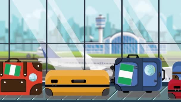 Maletas con pegatinas de bandera nigeriana en el carrusel de equipaje en el aeropuerto, primer plano. Viajar a Nigeria animación de dibujos animados loopable relacionados — Vídeo de stock