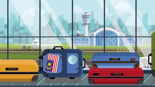 Equipaje con pegatinas de bandera malaya en carrusel en el aeropuerto, primer plano. Viajar a Malasia animación de dibujos animados loopable relacionados — Vídeo de stock
