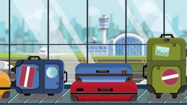 Koffers met Letse vlag stickers op Bagage carrousel in luchthaven, close-up. Reis naar Letland gerelateerde loop bare cartoon animatie — Stockvideo