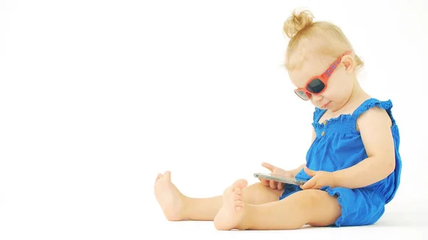 Focado bebê menina usando óculos de sol relógios filme ou desenho animado em um smartphone — Fotografia de Stock