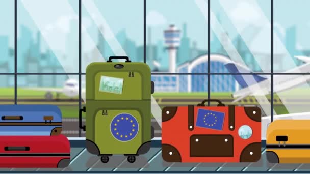 Чемоданы со стикерами с флагом ЕС на багажной карусели в аэропорту, крупным планом. Европейская анимация, связанная с туризмом — стоковое видео