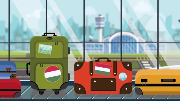 Чемоданы с венгерскими наклейками на багажной карусели в аэропорту, крупным планом. Туризм в Венгрии, связанная с мультяшной анимацией — стоковое видео