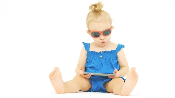 Bebê sério usando óculos de sol olha para o smartphone — Fotografia de Stock