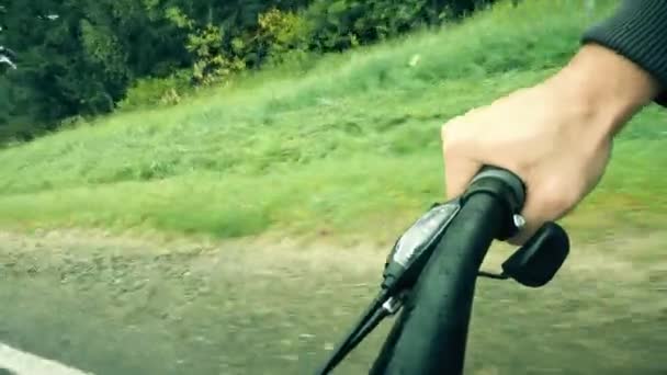 Dłoń na uchwycie rowerowym podczas jazdy wzdłuż drogi leśnej — Wideo stockowe