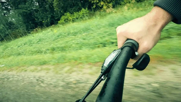 Mano en un agarre de bicicleta mientras se conduce a lo largo del camino forestal —  Fotos de Stock