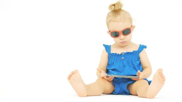 Bebê sério usando óculos de sol assiste filme ou desenho animado em um smartphone moderno — Fotografia de Stock