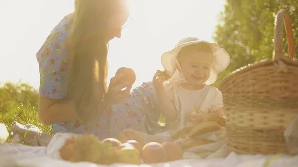 Веселая маленькая девочка и ее мама устраивают пикник в летний день — стоковое фото