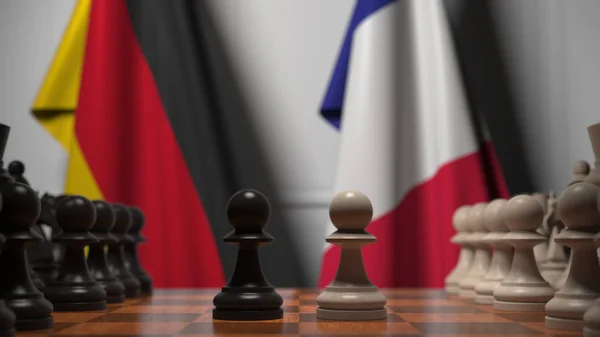 Flaggen von Deutschland und Frankreich hinter Schachbrettern. Der erste Bauer zieht zu Beginn der Partie. politische Rivalität konzeptionelle 3D-Darstellung — Stockfoto