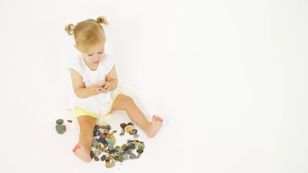 Menina loira brinca com seixo do mar. Clipe de férias relacionadas — Fotografia de Stock