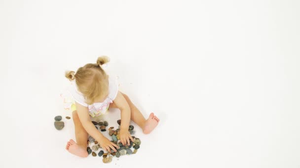 Blonďatá holčička hraje s mořskými oblázky. Klip související s dovolenou — Stock video