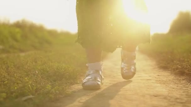 Steadicam-Aufnahme eines kleinen Mädchens, das an einem sonnigen Tag den Feldweg entlang geht, Füße aus nächster Nähe — Stockvideo