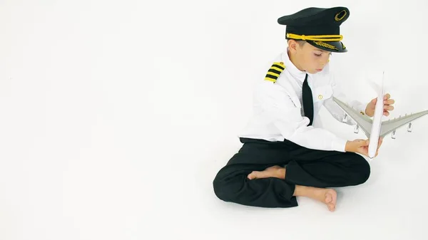 Niño vistiendo uniforme de pilotos juega con juguete avión comercial — Foto de Stock