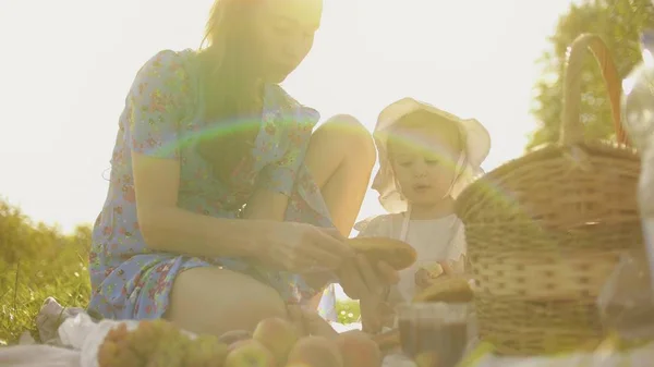 Pequena menina e sua mãe fazendo piquenique juntos em um dia ensolarado de verão — Fotografia de Stock