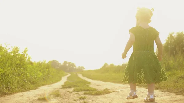 Menina bebê andando ao longo do caminho do campo rural em uma noite de verão ensolarada — Fotografia de Stock