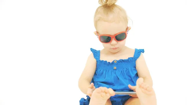 Retrato de uma menina usando óculos de sol e vestido azul com um smartphone moderno. Aplicativos relacionados a férias — Fotografia de Stock