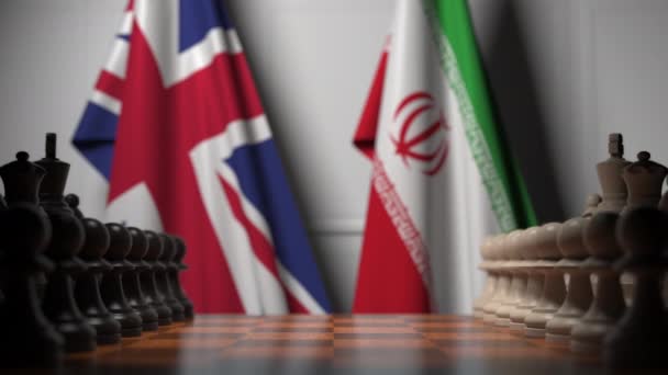 Yhdistyneen kuningaskunnan ja Iranin liput shakkilaudan sotilaiden takana. Shakkipeli tai poliittiseen kilpailuun liittyvä 3D-animaatio — kuvapankkivideo