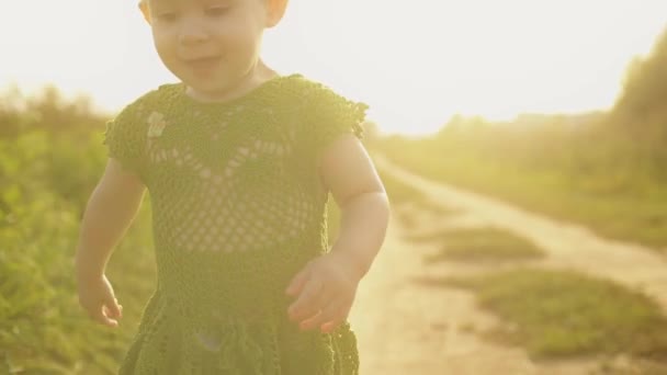 Glimlachend baby meisje loopt langs landelijk veldpad op een zonnige zomeravond — Stockvideo