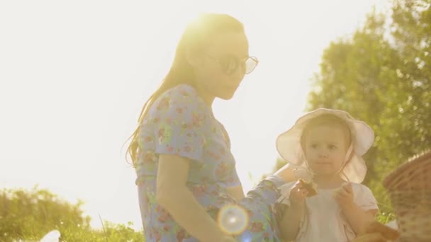 Νεαρή γυναίκα και το μικρό κοριτσάκι της έχουν πικνίκ σε μια όμορφη καλοκαιρινή μέρα — Αρχείο Βίντεο