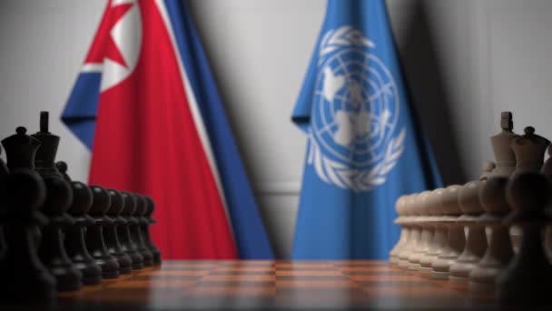 Nordkoreas och Förenta nationernas flaggor bakom brickor på schackbrädet. Konceptuell redaktionell 3D-animation — Stockvideo