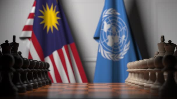 Флаги Малайзии и ООН за пешками на шахматной доске. Концептуальная редакционная 3D анимация — стоковое видео