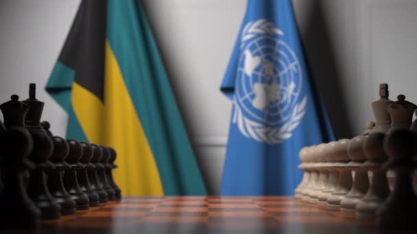 Bahamas och Förenta nationernas flaggor bakom brickor på schackbrädet. Konceptuell redaktionell 3D-animation — Stockvideo