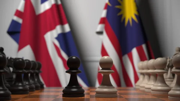 Vlajky Velké Británie a Malajsie za pěšáky na šachovnici. Šachy nebo politická rivalita související 3D vykreslování — Stock fotografie