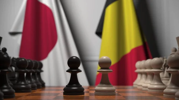 Bandiere del Giappone e del Belgio dietro pedoni sulla scacchiera. Rendering 3D relativo alla partita a scacchi o alla rivalità politica — Foto Stock